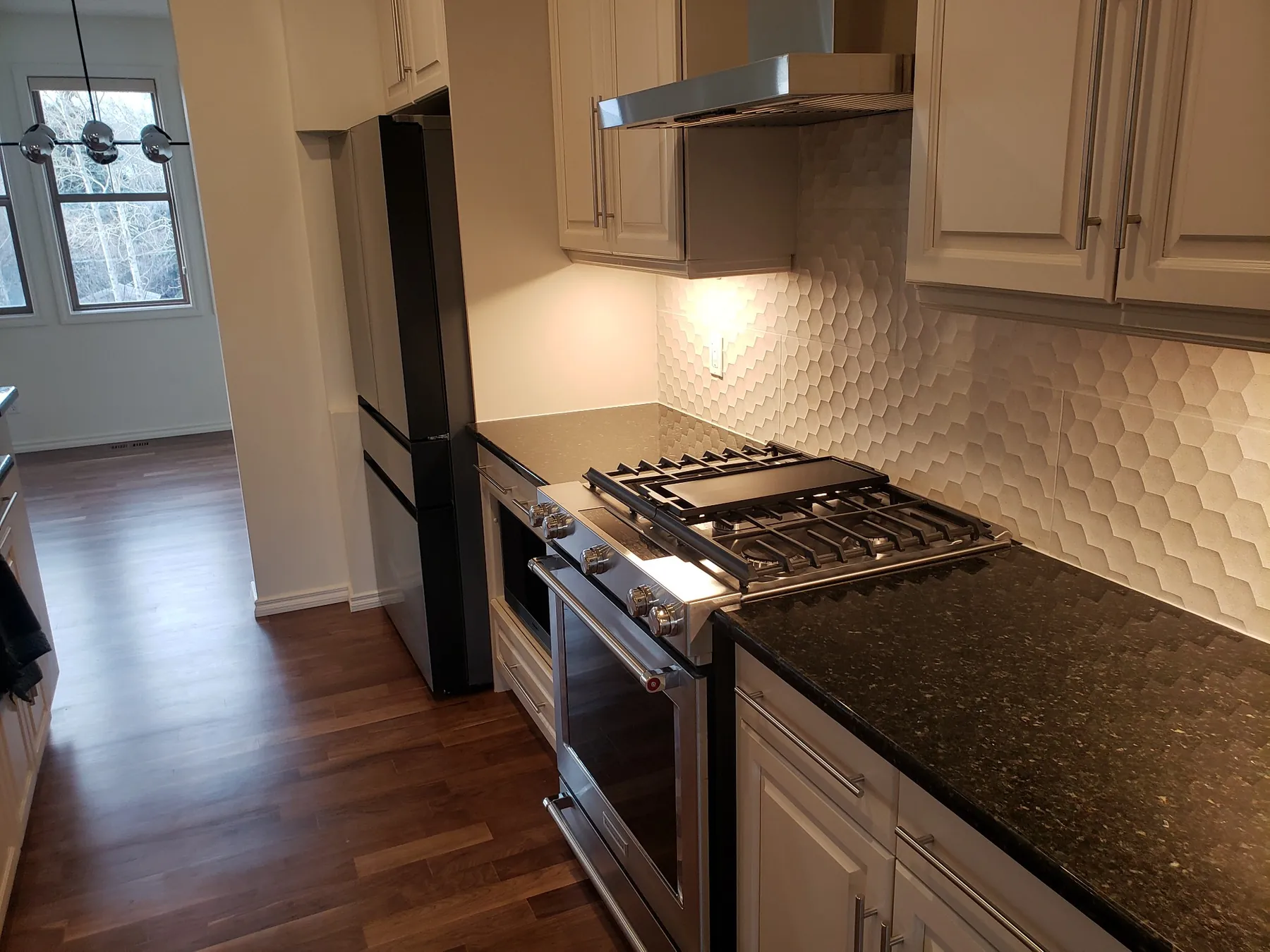 Renovated Calgary kitchen with white cabinetry, dark countertops and backsplash detail